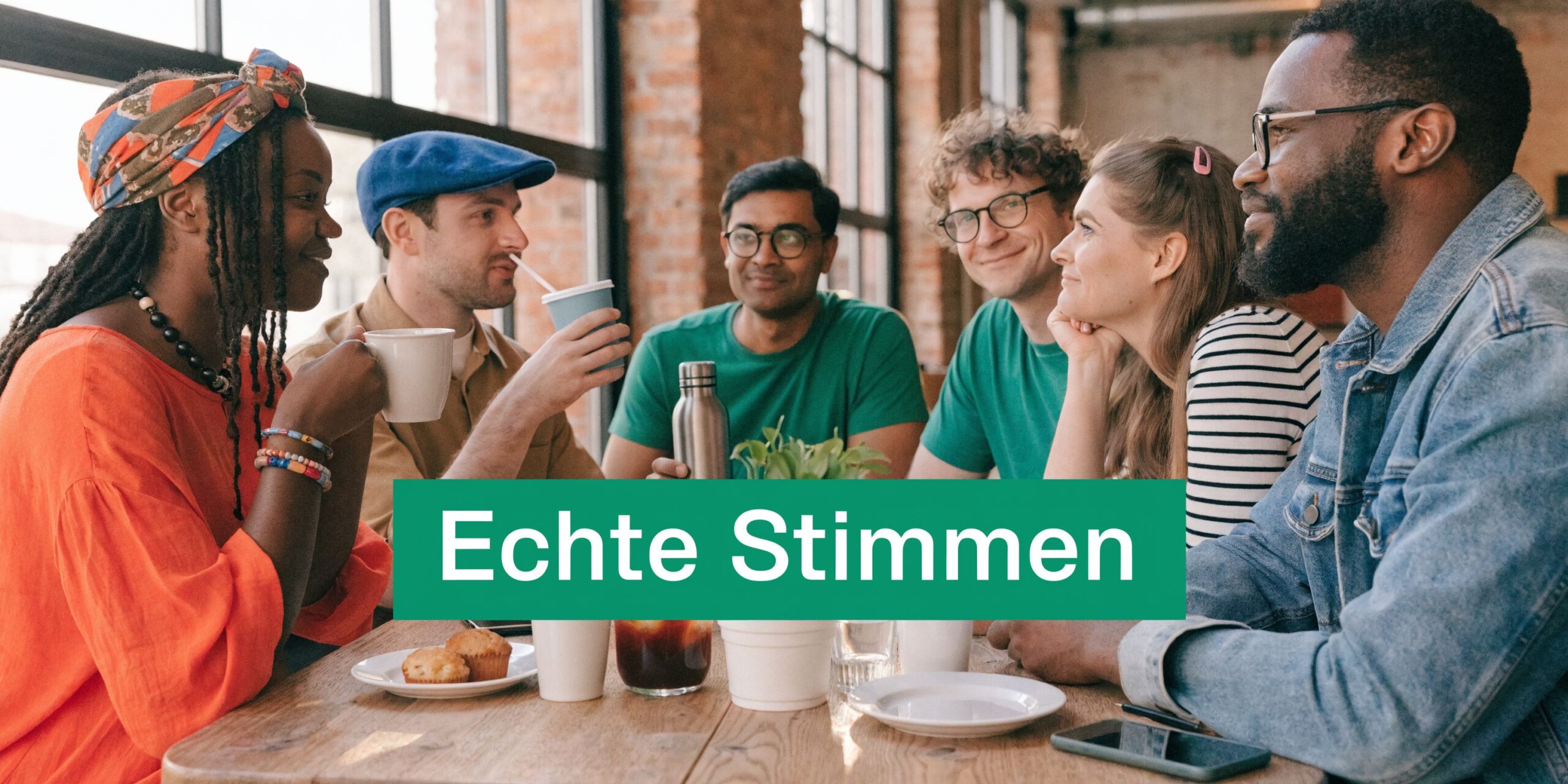 Eine vielfältige Gruppe junger Erwachsener unterhält sich fröhlich an einem Tisch in einem modernen Café mit Backsteinwänden.