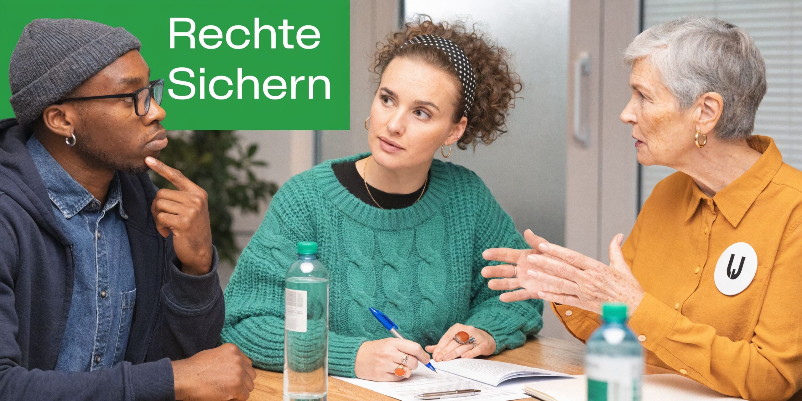Drei Personen sitzen an einem Tisch und diskutieren über arbeitsrechtliche Angelegenheiten in einem professionellen Umfeld.