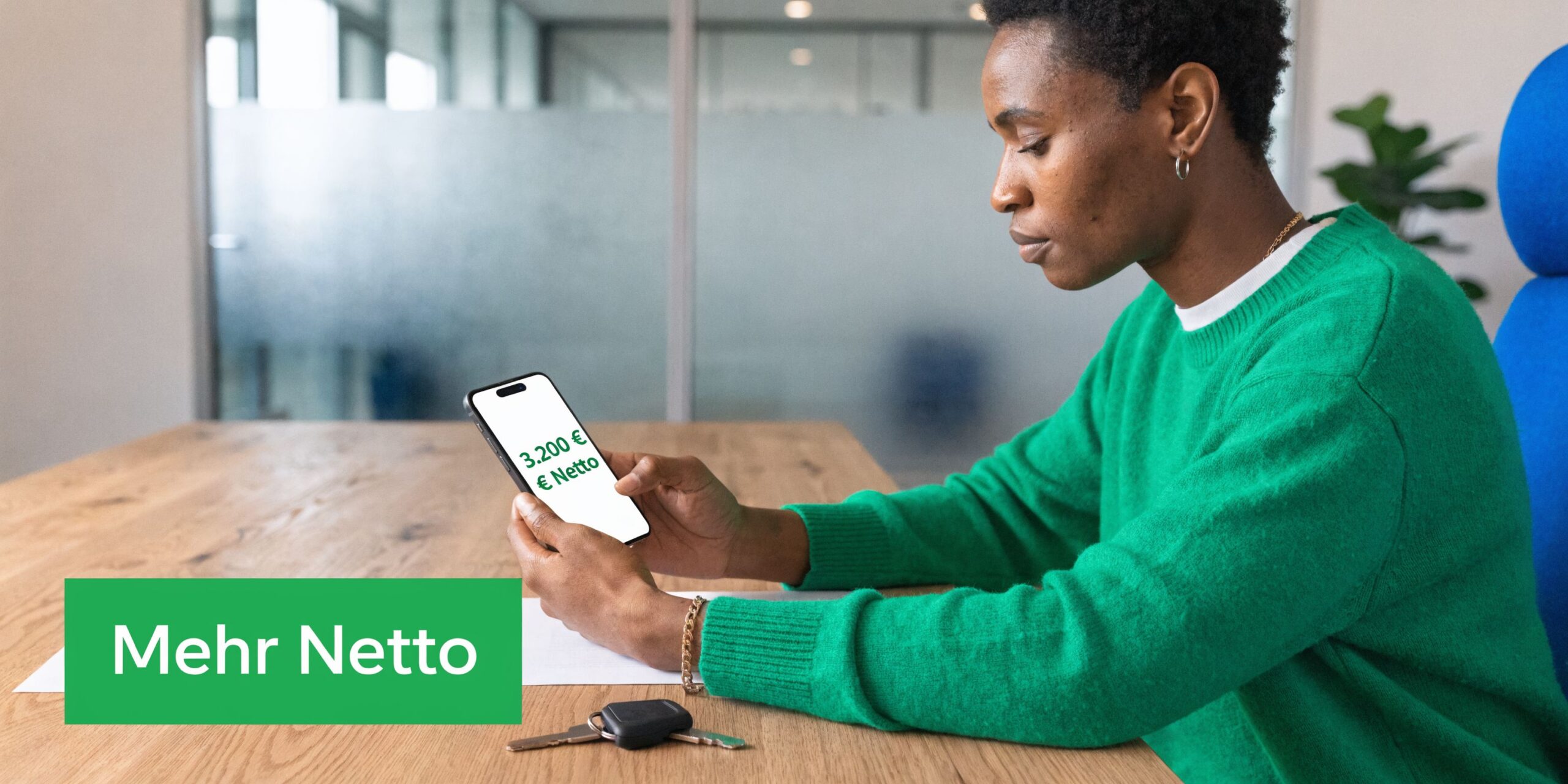 Eine Person betrachtet ihr Gehalt auf einem Smartphone an einem Holztisch mit einem Autoschlüssel daneben.