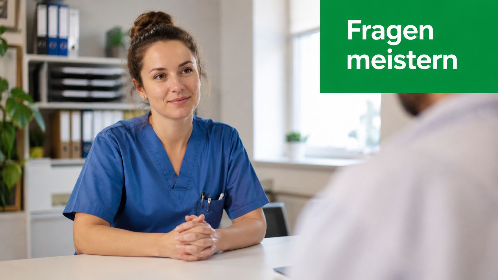 Eine freundliche Pflegefachkraft in blauer Arbeitskleidung sitzt in einem Büro und führt ein aufmerksames Gespräch.