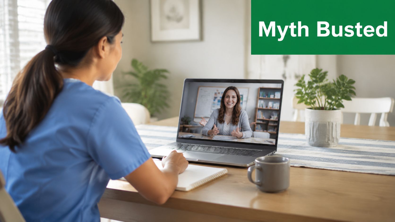 Eine Frau in Arbeitskleidung führt ein Video-Meeting am Laptop an einem hölzernen Esstisch im Homeoffice.