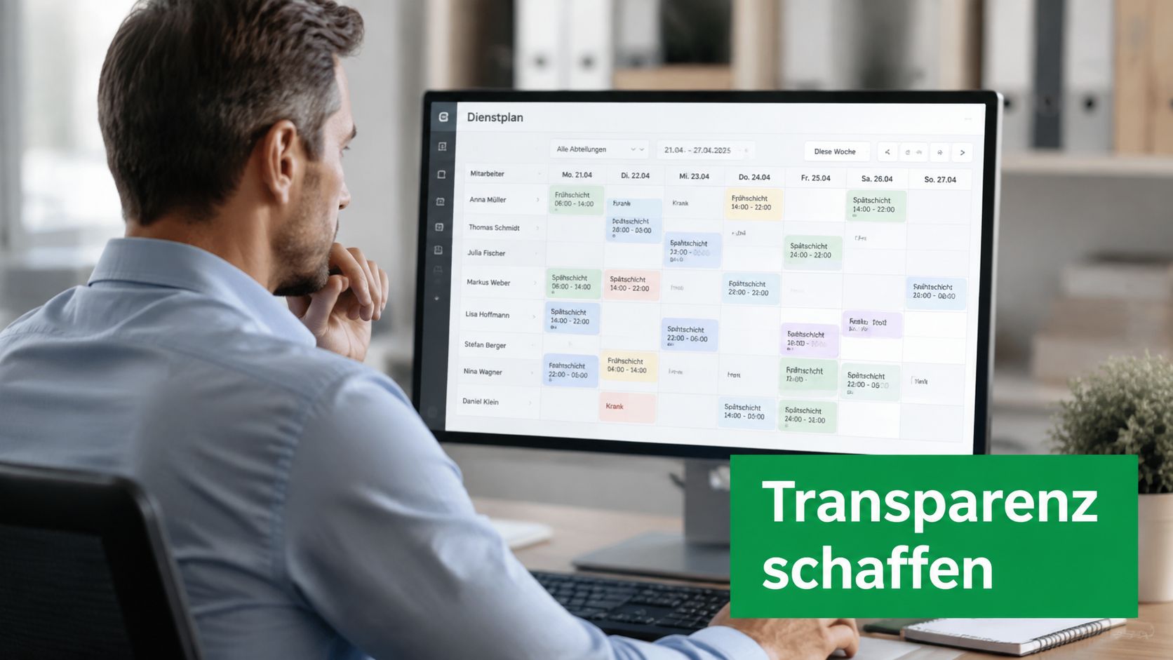 Ein Mann betrachtet an einem Computerbildschirm einen digitalen Dienstplan für Mitarbeiter in einer modernen Büroumgebung.