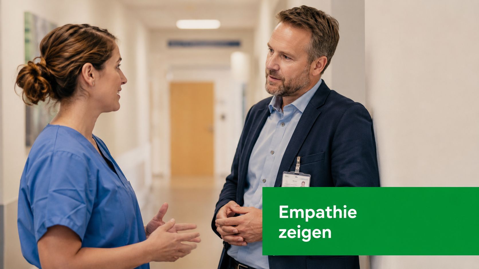 Eine weibliche Pflegekraft und ein männlicher Vorgesetzter führen ein empathisches Gespräch in einem Krankenhausflur.