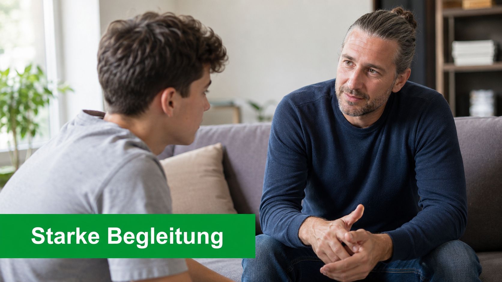 Ein Sozialpädagoge führt ein einfühlsames Beratungsgespräch mit einem Jugendlichen auf einer gemütlichen Couch im Wohnzimmer.